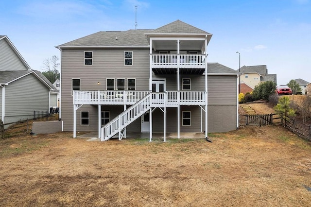 back of property featuring a wooden deck, a balcony, and a yard