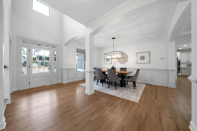 entryway with ornamental molding, wood-type flooring, and a notable chandelier