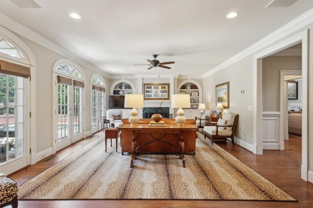 interior space featuring ornamental molding, built in features, a fireplace, ceiling fan, and hardwood / wood-style flooring