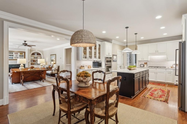 dining area with light wood-type flooring, crown molding, and ceiling fan