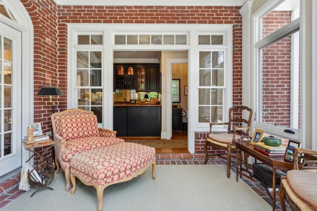 sitting room featuring plenty of natural light and brick wall