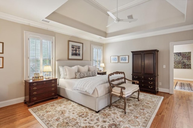 bedroom with light hardwood / wood-style flooring, ceiling fan, a raised ceiling, and ornamental molding