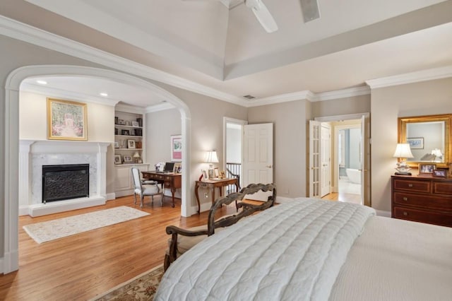 bedroom featuring light hardwood / wood-style flooring, ceiling fan, a high end fireplace, and ornamental molding