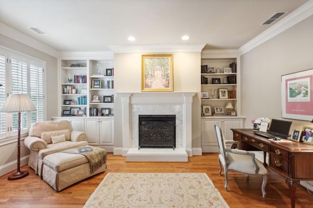 office space featuring light hardwood / wood-style flooring, crown molding, a high end fireplace, and built in shelves