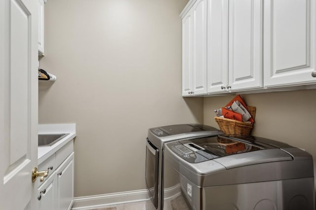 clothes washing area with sink, washing machine and clothes dryer, cabinets, and light tile patterned floors