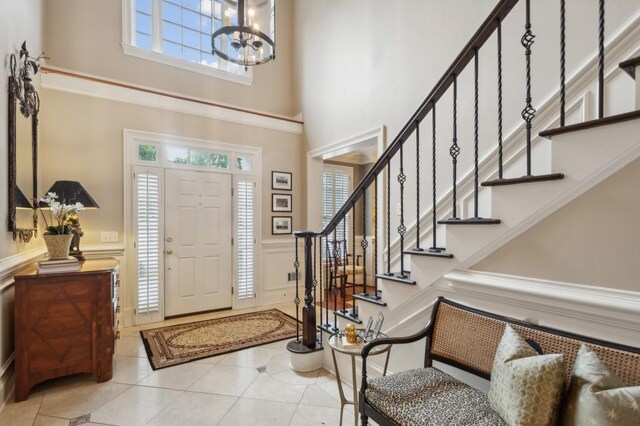 entryway with a high ceiling, tile patterned flooring, and an inviting chandelier