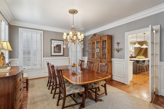 dining space featuring light wood-type flooring, crown molding, and a chandelier