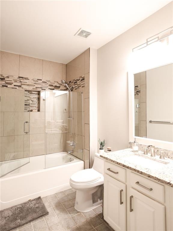 full bathroom featuring bath / shower combo with glass door, tile patterned floors, vanity, and toilet