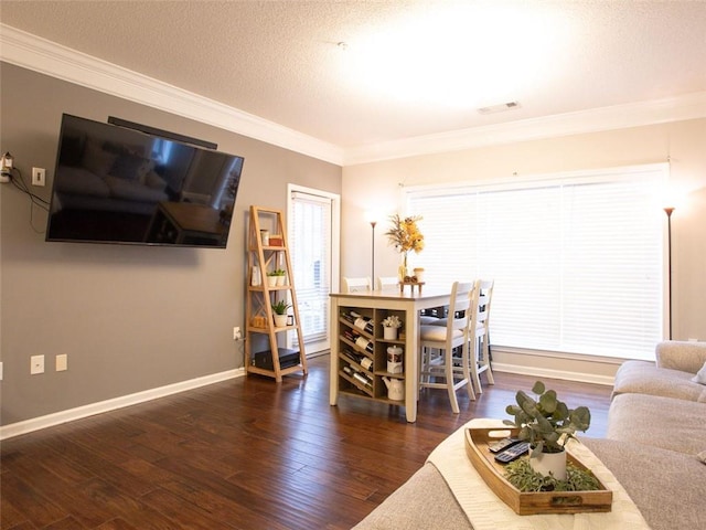 living room featuring dark wood-type flooring, ornamental molding, and a textured ceiling