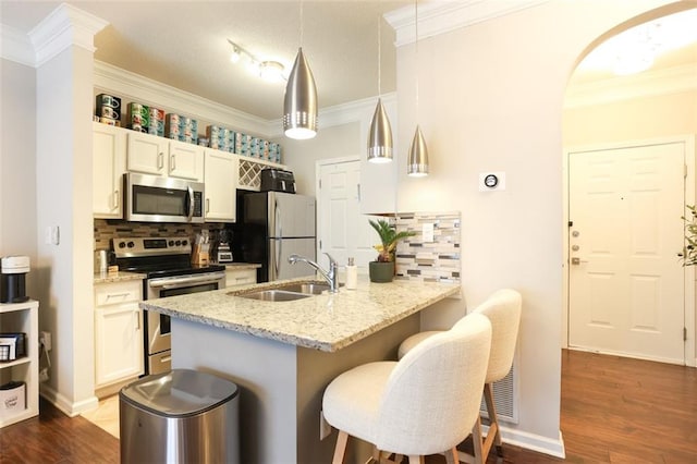 kitchen with decorative light fixtures, sink, a breakfast bar area, stainless steel appliances, and light stone countertops