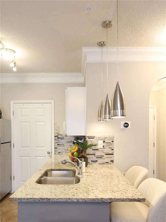 kitchen featuring tasteful backsplash, hanging light fixtures, crown molding, and sink