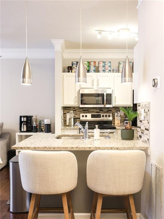 kitchen featuring white cabinetry, stainless steel appliances, decorative light fixtures, and light stone counters