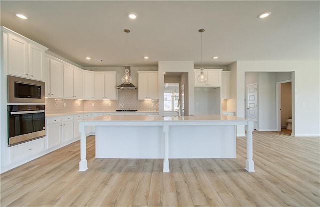 kitchen featuring a center island with sink, stainless steel oven, and white cabinets