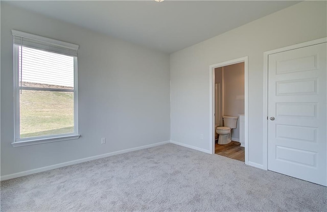 unfurnished bedroom featuring light colored carpet and ensuite bathroom