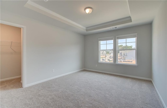 empty room featuring ornamental molding, a raised ceiling, and carpet floors