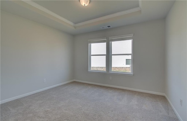 carpeted empty room featuring ornamental molding and a tray ceiling