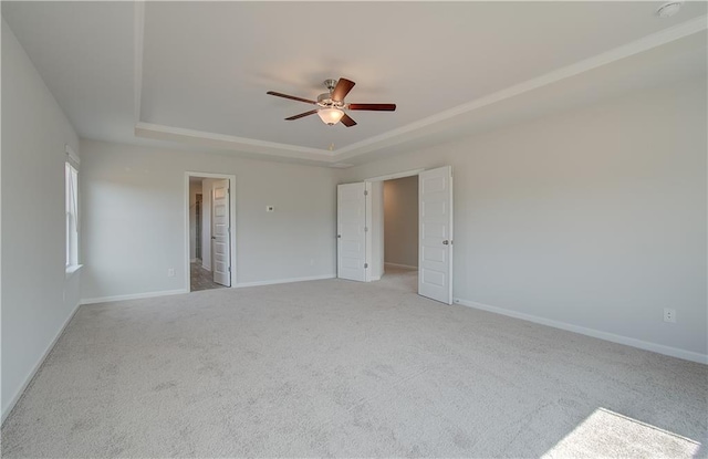 empty room featuring light colored carpet, ceiling fan, and a tray ceiling