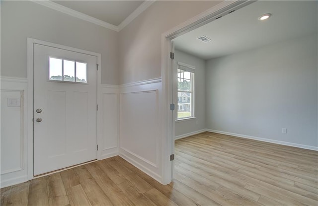 foyer with crown molding and light hardwood / wood-style floors