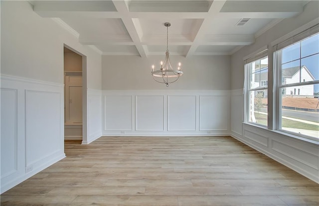 unfurnished dining area with beamed ceiling, coffered ceiling, an inviting chandelier, and light wood-type flooring