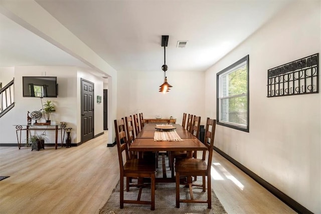 dining room with light wood-style floors, stairway, and baseboards