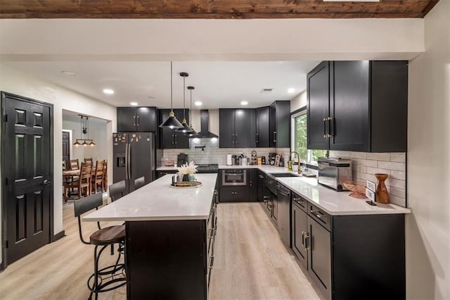 kitchen with refrigerator with ice dispenser, light wood-type flooring, wall chimney exhaust hood, a sink, and a breakfast bar