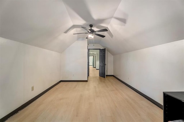 additional living space featuring light wood-style flooring, baseboards, a ceiling fan, and vaulted ceiling