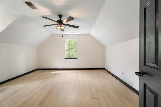 additional living space with light wood-style flooring, baseboards, ceiling fan, and vaulted ceiling