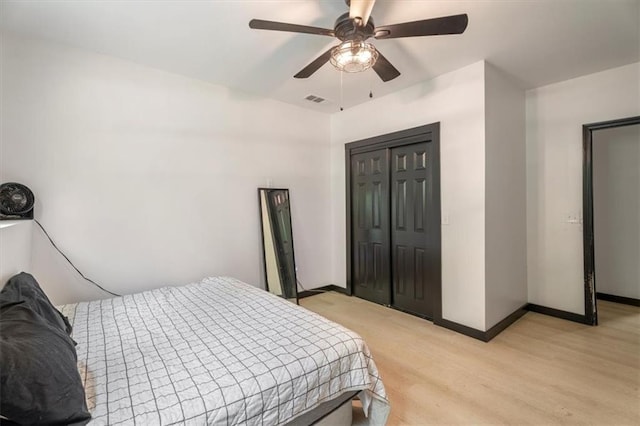 bedroom with baseboards, a closet, ceiling fan, and light wood-style floors