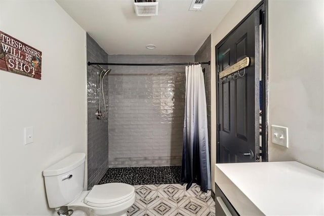bathroom featuring toilet and a tile shower