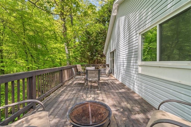 deck with outdoor dining space and a fire pit