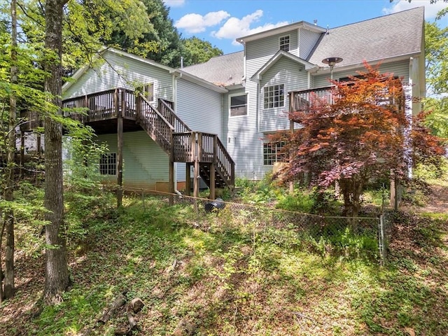 rear view of house featuring a fenced backyard, a deck, a shingled roof, and stairway