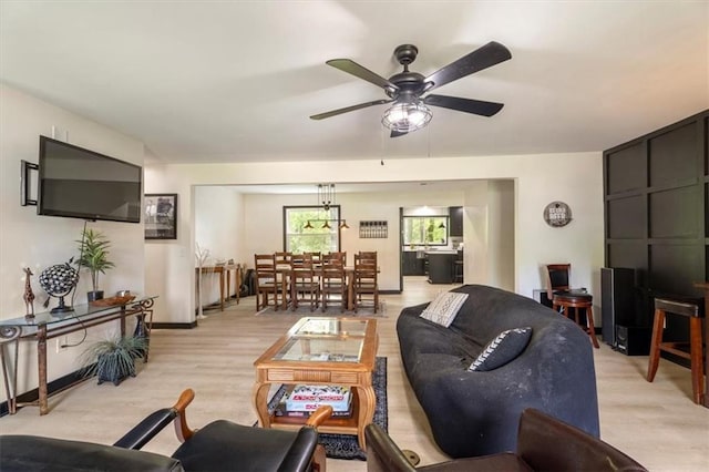 living area featuring a ceiling fan, light wood-style flooring, and baseboards