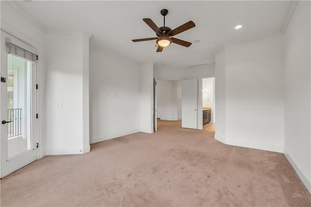 unfurnished bedroom featuring light carpet, baseboards, ensuite bath, ceiling fan, and ornamental molding