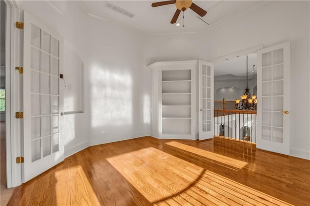 interior space featuring baseboards, visible vents, wood finished floors, french doors, and ceiling fan with notable chandelier