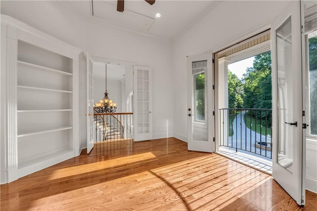 entryway featuring ceiling fan with notable chandelier, wood finished floors, baseboards, built in features, and french doors