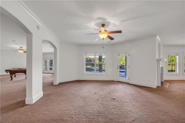 unfurnished living room featuring ornamental molding, arched walkways, and light carpet