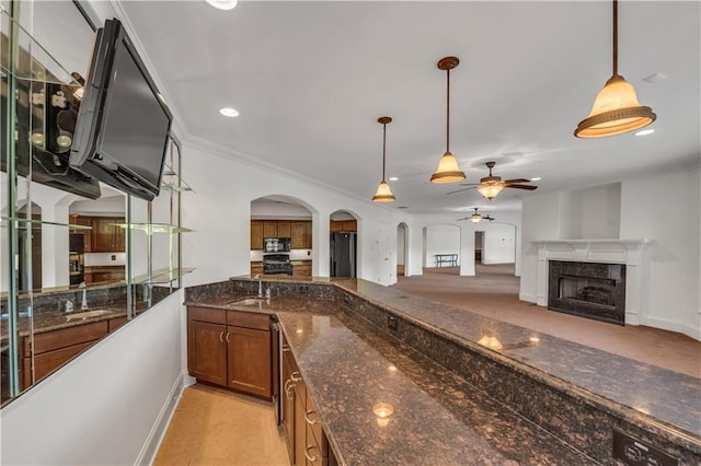 kitchen featuring open floor plan, dark stone countertops, a sink, and decorative light fixtures