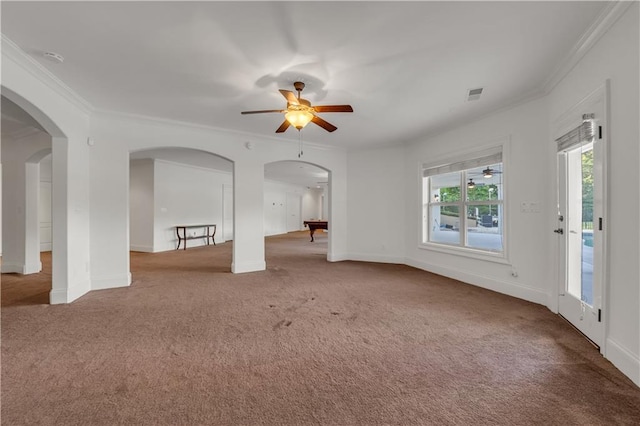 carpeted spare room with arched walkways, visible vents, crown molding, and baseboards