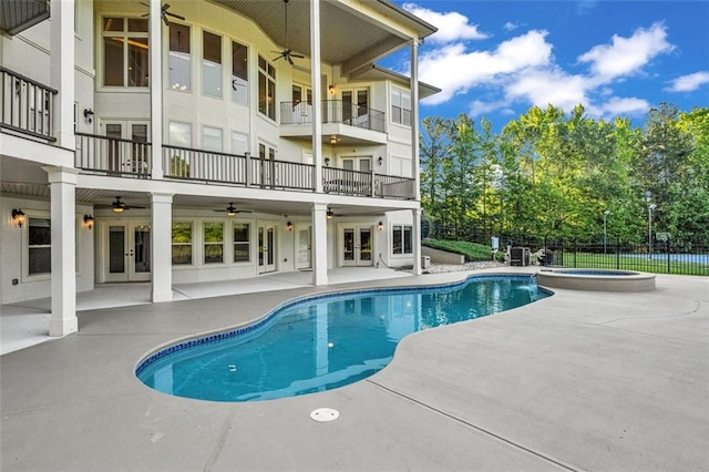 view of swimming pool featuring french doors, a patio, a pool with connected hot tub, ceiling fan, and fence