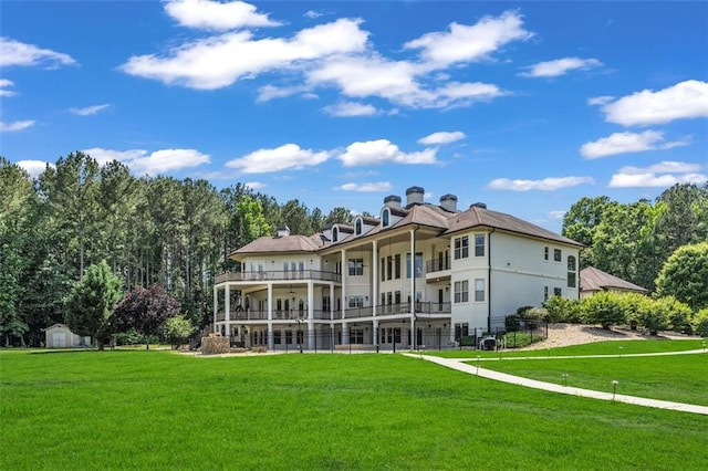 back of property featuring an outbuilding, a lawn, a balcony, and a storage shed