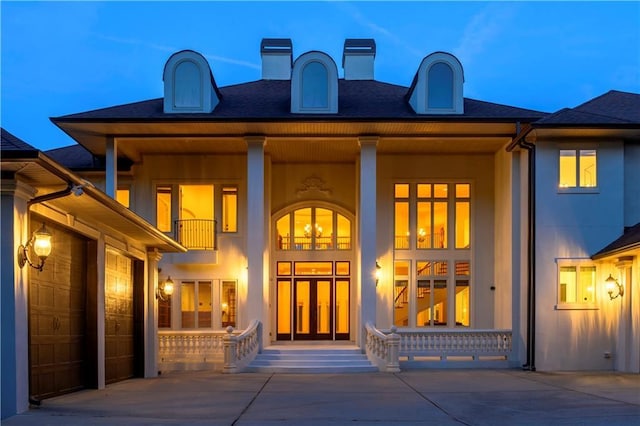 property entrance with a garage, covered porch, a balcony, and stucco siding