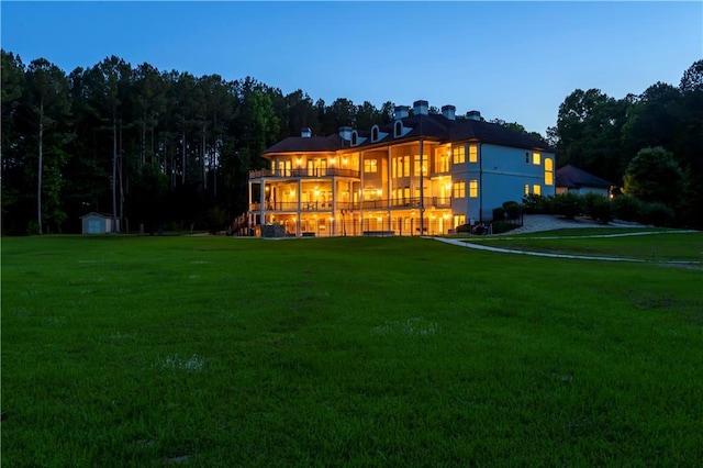 back of property with a yard, a storage unit, and a balcony