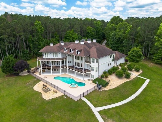 rear view of house with a patio area, a fenced backyard, a yard, and a forest view