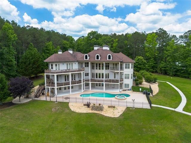 back of property with a balcony, a patio area, stairway, and a fenced in pool