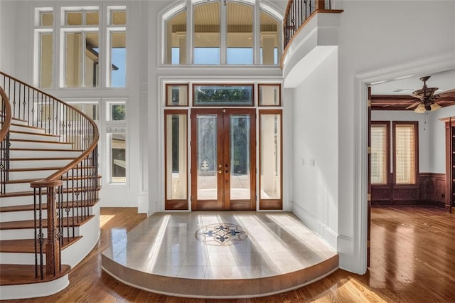 foyer with french doors, stairway, wood finished floors, and a high ceiling