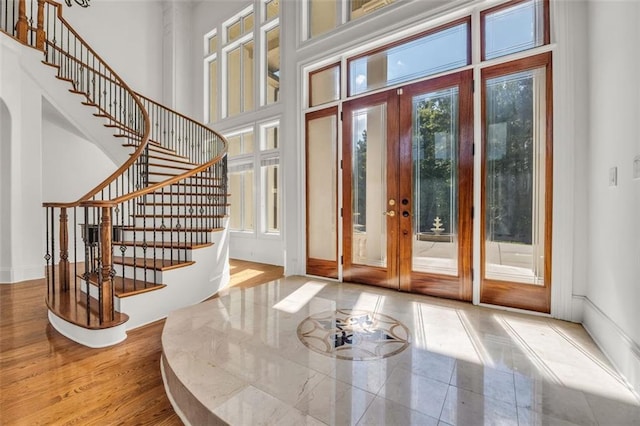 foyer entrance with french doors, plenty of natural light, and a towering ceiling