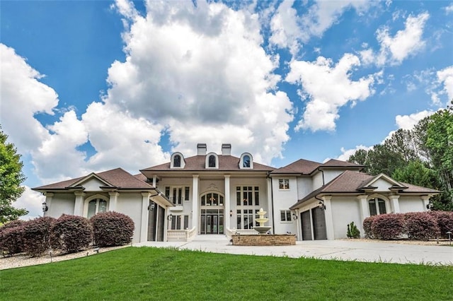 rear view of property with an attached garage, a lawn, concrete driveway, and stucco siding