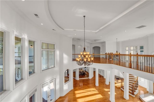 hall featuring a chandelier, recessed lighting, visible vents, light wood-type flooring, and a raised ceiling