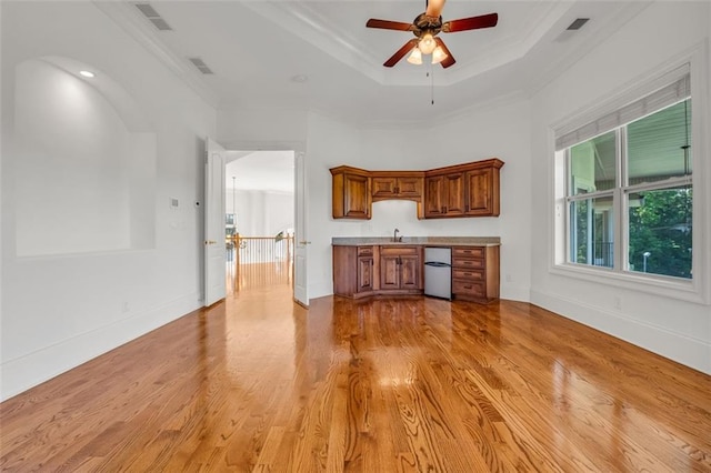 interior space with a tray ceiling, visible vents, light countertops, and light wood-style flooring