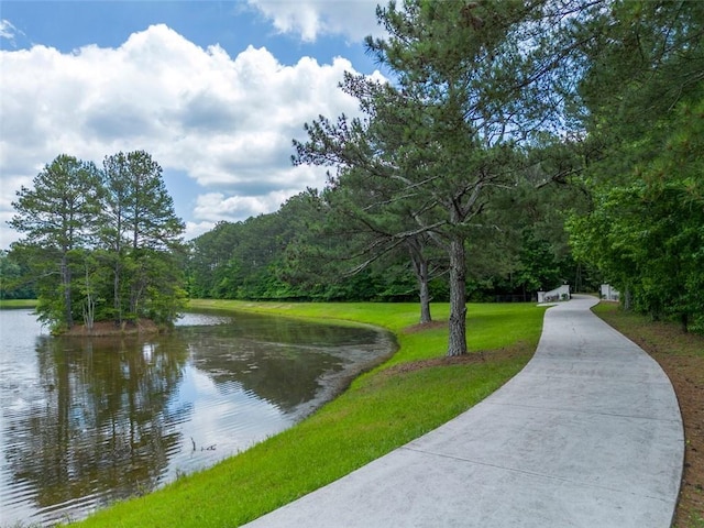 view of home's community with a water view and a lawn